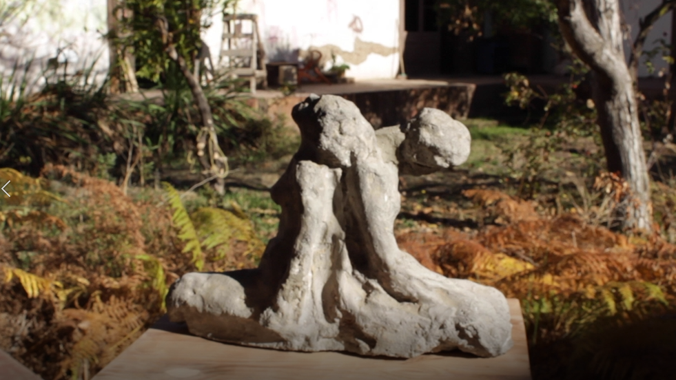 Escultura de piedra que ilustra dos cuerpos apoyados espalda con espalda, en evidente cansancio. 