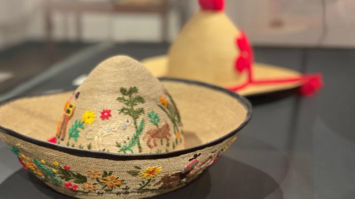Fotografía que muestra un sombrero de paja de teatina tejida, su forma imita al bonete huicano, tanto en la parte externa del ala como en la copa posee coloridos bordados de lana con motivos costumbristas.