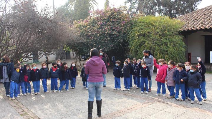 Se aprecia un grupo de niños y niñas junto a sus educadoras disfrutando de una visita mediada, algunos de estos infantes entusiasmados levantan su mano para responder una pregunta.
