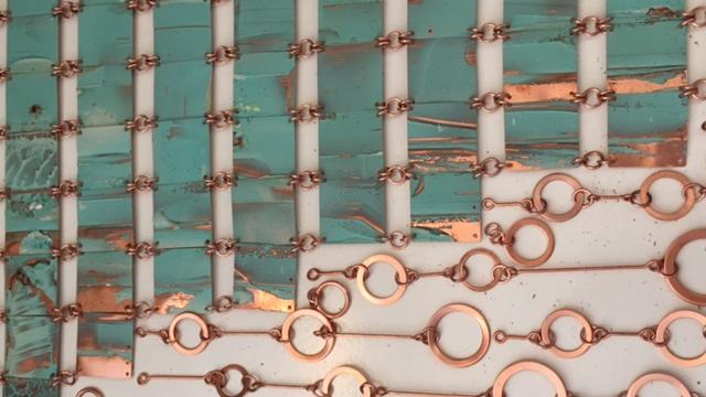 Tejido de láminas de cobre, compuesta de cuadrados en cobre oxidado, unidos a eslabones circulares de cobre pulido.