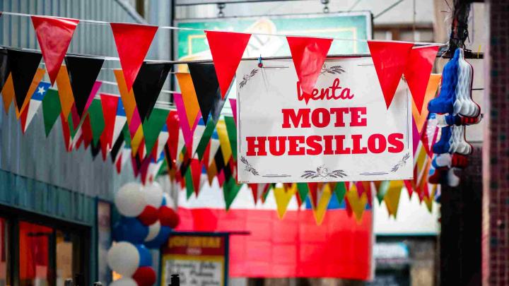 Muchos banderines de colores colgados y un letrero blanco con letras rojas que dice Mote con Huesillos