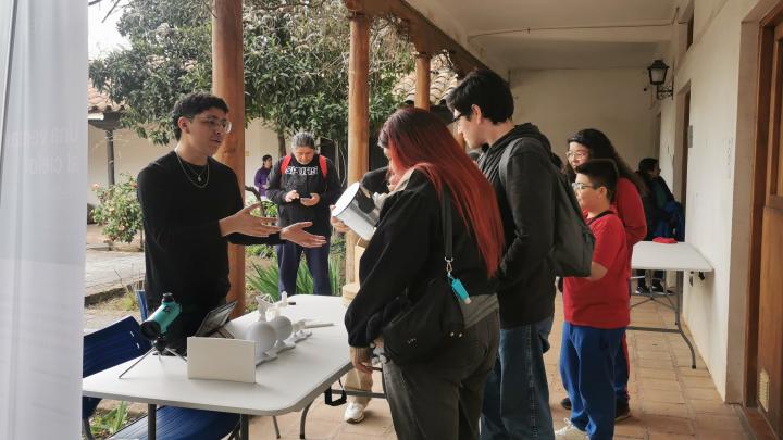 un joven muestra a grupo de adolescentes como fucniona un telescopio virtual