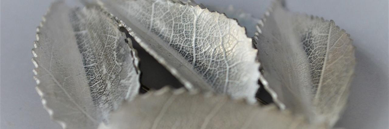 Fotografía que retrata cuatro hojas confeccionadas en plata por una artesana orfebre