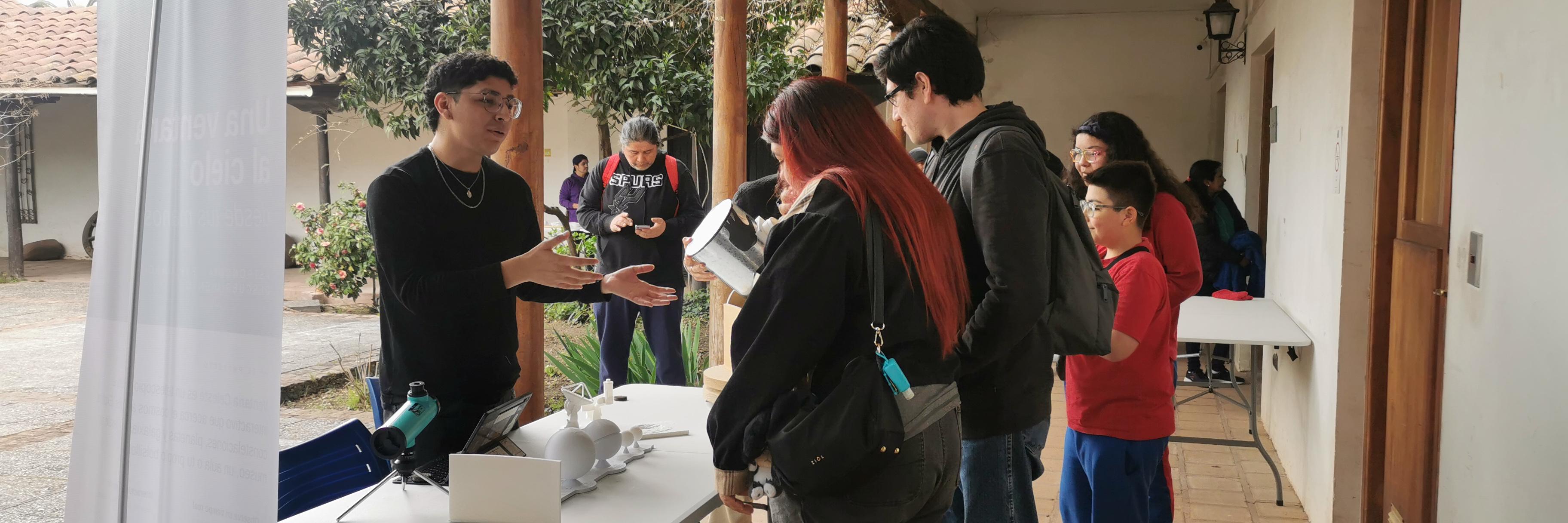 un joven muestra a grupo de adolescentes como fucniona un telescopio virtual