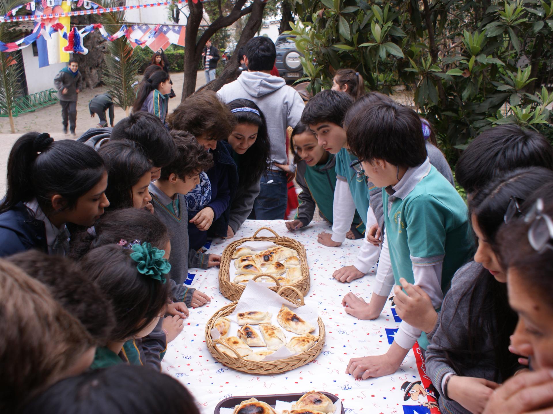 Niños y niñas rodeando una mesa que contiene canastas de empanadas de horno