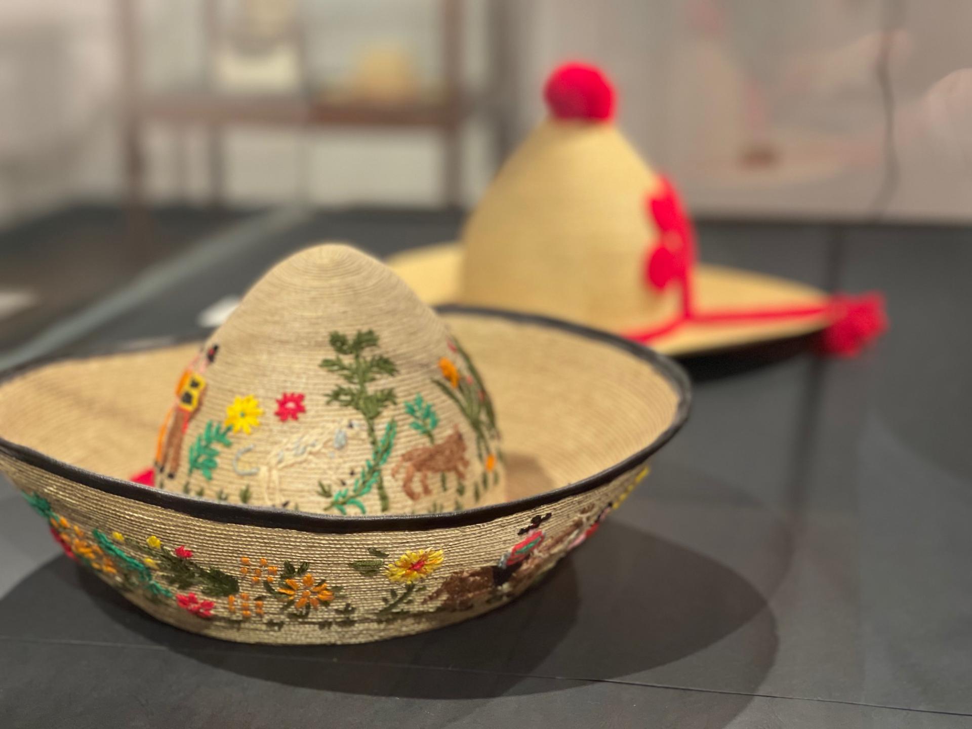 Fotografía que muestra un sombrero de paja de teatina tejida, su forma imita al bonete huicano, tanto en la parte externa del ala como en la copa posee coloridos bordados de lana con motivos costumbristas.