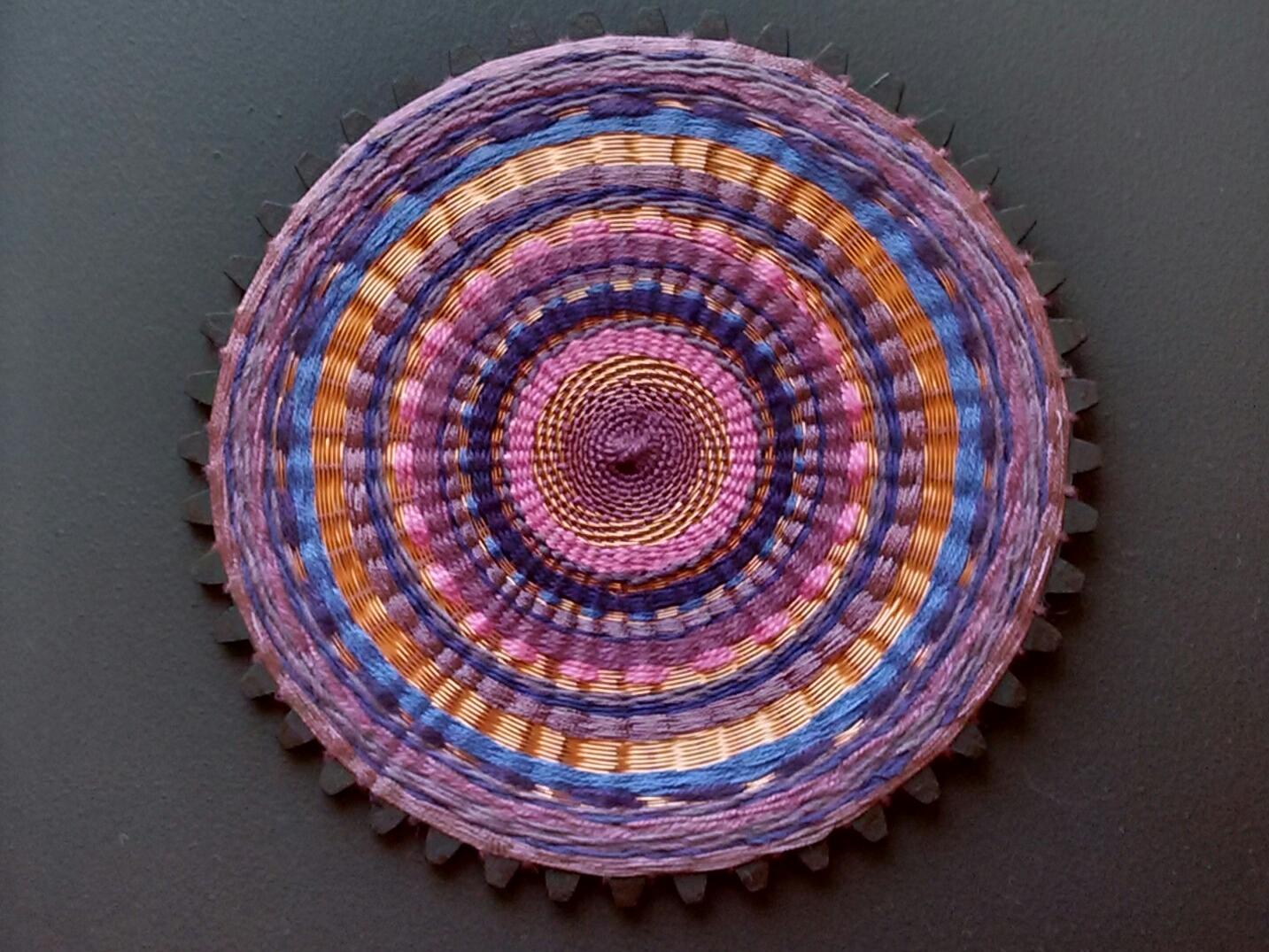 Cuadro textil circular en tonor purpuras y naranjas