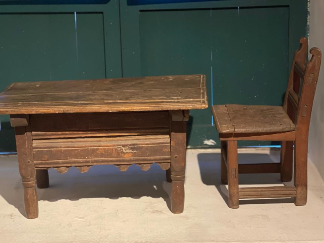 Fotografía a color donde se aprecia una mesa y silla de madera, ambos para uso de un niño pequeño.