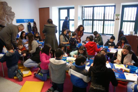 grupo de niños, niñas y adultos dibujando y pintando en la sala didáctica del museo