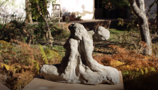 Escultura de piedra que ilustra dos cuerpos apoyados espalda con espalda, en evidente cansancio. 