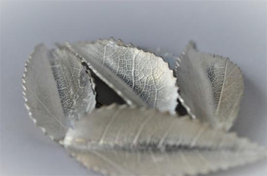 Fotografía que retrata cuatro hojas confeccionadas en plata por una artesana orfebre