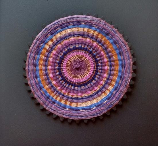 Artesanía textil circular en tonos morado y naranjas 