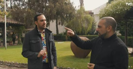 Imagen que muestra dos personas adultas conversando, en el fondo se aprecia un patio lleno de árboles y vegetación en tonos verdes. 