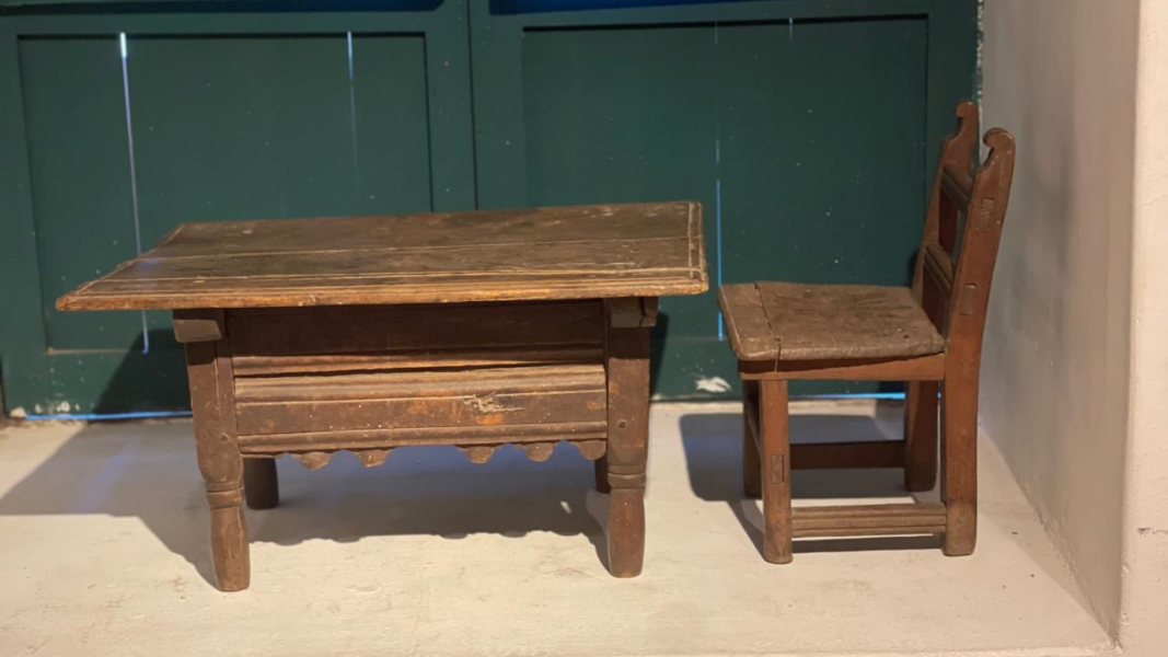 Fotografía a color donde se aprecia una mesa y silla de madera, ambos para uso de un niño pequeño.